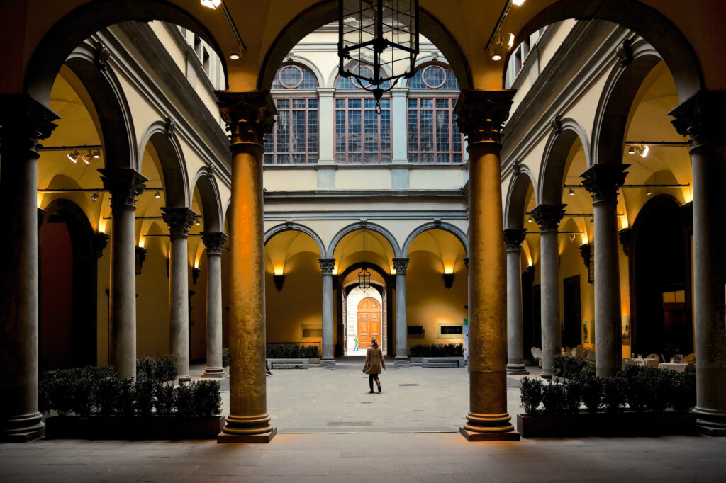 Courtyard view of Palazzo Medici Riccardi in Florence, Italy, showcasing Renaissance architecture and a lone figure.