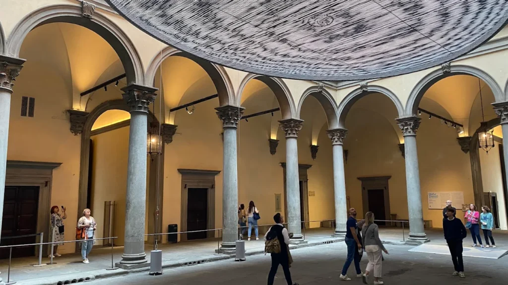 Palazzo Strozzi Firenze courtyard with arched columns and a modern art installation overhead.